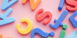 a pile of plastic letters and numbers on a pink and blue background