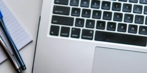 silver laptop computer beside white ruled paper